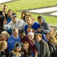 students taking selfies with T. Haas and his wife at a GVSU football game